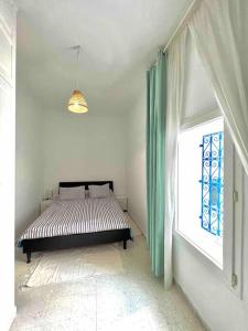 ein Schlafzimmer mit einem Bett in einem Zimmer mit einem Fenster in der Unterkunft The Blue Sea View Sidi Bou Said in Sidi Bou Saïd