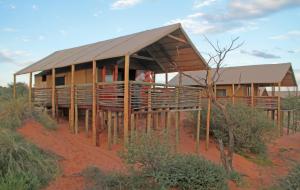 a house in the middle of a field at Suricate Tented Kalahari Lodge in Hoachanas