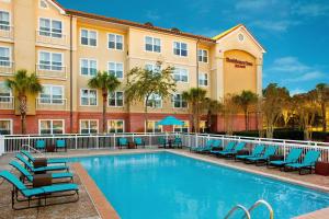a hotel with a swimming pool with chairs and a building at Residence Inn Sandestin at Grand Boulevard in Destin