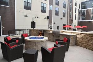 une terrasse avec un foyer extérieur, des chaises et un grill dans l'établissement TownePlace Suites by Marriott Lawrence Downtown, à Lawrence