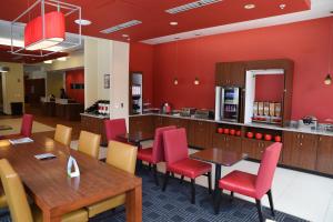 restauracja z czerwonymi ścianami oraz drewnianymi stołami i krzesłami w obiekcie TownePlace Suites by Marriott Lawrence Downtown w mieście Lawrence
