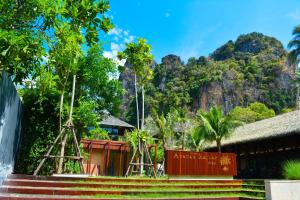 a building with stairs and a waterfall in front of a mountain at Avatar Railay in Railay Beach