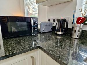 a kitchen with a counter top with a microwave at Incredible Private Rooms All with Private Bathrooms in a Fully Serviced House next to City Centre with Free Parking in Coventry +55 photos