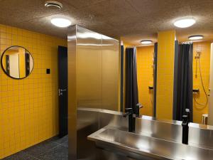 a bathroom with two sinks and a mirror and yellow tiles at City Hostel Bergen in Bergen