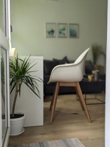 a white chair in a living room with a plant at Zara Green Apartment 4 Guests Pet Friendly in Stara Zagora