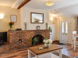 a living room with a brick fireplace and a mirror at Sunnyside Cottage in Crossens
