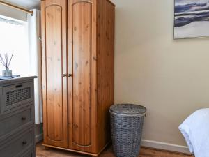 a bedroom with a wooden cabinet and a trash can at Sunnyside Cottage in Crossens