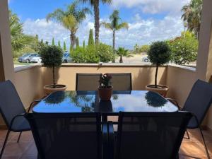 una mesa y sillas en un balcón con palmeras en Quinta da Boa Nova - Cheerful and spacious 2-bedroom duplex, en Estômbar