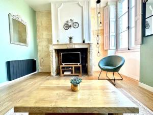 een woonkamer met een tafel, een stoel en een televisie bij CHARMANT T2 HYPER-CENTRE BORDEAUX in Bordeaux