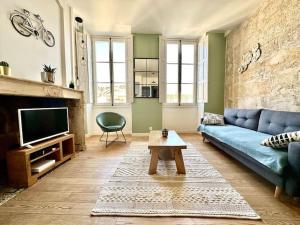 een woonkamer met een blauwe bank en een tv bij CHARMANT T2 HYPER-CENTRE BORDEAUX in Bordeaux
