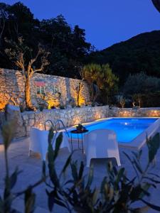 - une piscine avec 2 chaises blanches et une table la nuit dans l'établissement Holiday House - Old Olive, à Porozina