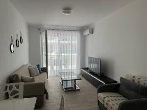 a living room with a couch and a tv at Marjana's Sea View Apartment 1 in Lezhë