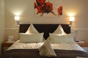 バート・ベヴェンセンにあるLandhaus Zum Heidewandererのベッドルーム1室(白いシーツと赤い花のベッド付)