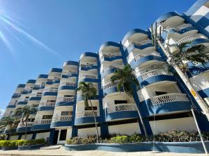 un edificio azul con palmeras delante en A pasos de la playa! Acogedor apartamento en Bello Horizonte con Balcón I WiFi, en Playa Dormida