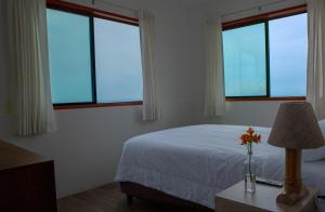 Casablanca del Mar في بونتا هيرموسا: غرفة نوم بثلاث نوافذ وسرير وطاولة بها مصباح