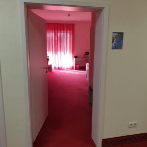 un corridoio con porta rosa e una stanza con finestra di Gästehaus Catherine a Zierenberg