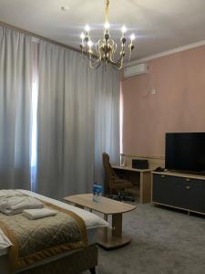 Dormitorio con cama, escritorio y TV en Думан Холл Отель, en Taraz