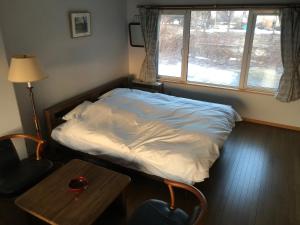 a bed in a room with a table and a window at つきのやど in Lake Toya