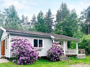 una pequeña casa con flores púrpuras delante de ella en Holiday home Backaryd II, en Backaryd