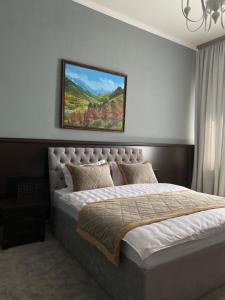 1 dormitorio con 1 cama con una pintura en la pared en Думан Холл Отель, en Taraz