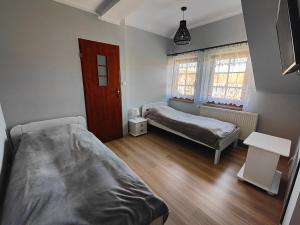 a bedroom with two beds and a table and windows at Pokoje gościnne u Izy in Tolkmicko