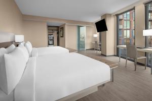 a bedroom with a large white bed and a dining room at AC Hotel by Marriott Washington DC Capitol Hill Navy Yard in Washington