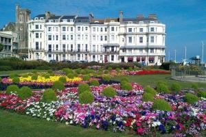 a large white building with a garden of flowers at 2 Bedroom Boutique Maisonette on Kings Road, St Leonards on Sea in St. Leonards