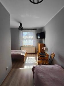 um quarto com 2 camas, uma secretária e uma janela em Pokoje gościnne u Izy em Tolkmicko