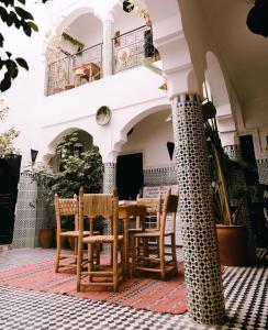un patio avec une table et des chaises dans un bâtiment dans l'établissement Riad Sijane, à Marrakech