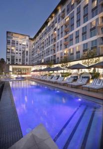 Johannesburg的住宿－Luxury 5-Star Hotel Apartment in Sandton，一座带椅子的大型游泳池以及一座大型建筑