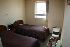 a hotel room with two beds and a window at Hotel Tetora Yunokawaonsen in Hakodate