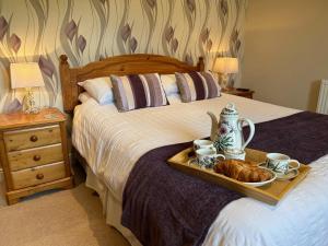 a bedroom with a bed with a tray of food on it at Ty Cerrig in Dyffryn