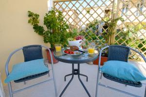 Kumquat studio Gouvia في جوفيا: طاولة مع صحن من الطعام و كرسيين