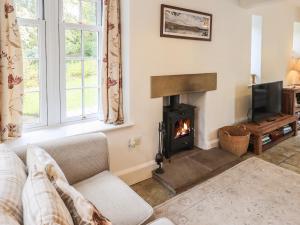 Una sala de estar con chimenea y un sofá. en The Old Post House at Low Stott Park, en Ulverston
