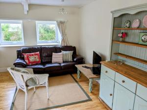 a living room with a leather couch and a table at Cosy Cottage Crundale 