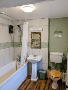 a bathroom with a sink and a toilet and a tub at Cosy Cottage Crundale 
