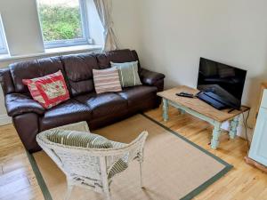 Cosy Cottage Crundale : غرفة معيشة مع أريكة جلدية بنية وطاولة