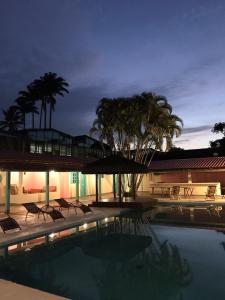 a swimming pool with chairs and trees at night at Pousada Maria Felipa Ilhabela in Ilhabela