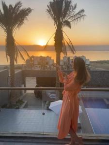 een vrouw die op een balkon staat te kijken naar haar mobiele telefoon bij laperla chalet villa di lusso deadsea in Sowayma