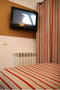 a tv on the wall of a bedroom with a bed at Costa do Sol B&B in Porto