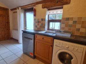 a kitchen with a washing machine and a sink at Sandpiper Cottage in Llanboidy