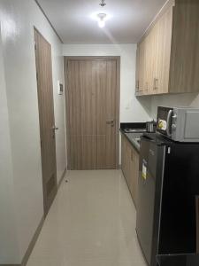 a kitchen with a black refrigerator and wooden cabinets at Shore 2 Staycation - Near Mall of Asia and Casinos in Manila