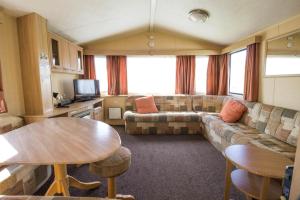 a living room with a couch and a table at Lovely 6 Berth Caravan At Naze Marine Holiday Park In Essex Ref 17275c in Walton-on-the-Naze