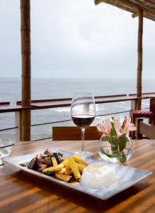 プンタ・エルモサにあるCasablanca del Marのテーブルの上に一皿とワイン1杯