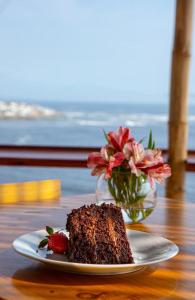 un trozo de pastel en un plato con un jarrón de flores en Casablanca del Mar en Punta Hermosa