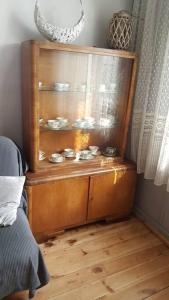 une armoire en bois avec de la vaisselle dans la chambre dans l'établissement Przytulnie i cicho w Ciechocinku, à Ciechocinek