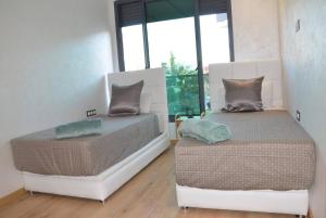 sypialnia z 2 łóżkami i oknem w obiekcie Appartement FES Hayat Luxury w Fezie
