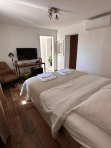 a white bedroom with two beds and a desk at Madonna Guest House in Dubrovnik