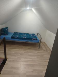 een kleine kamer met een blauw bed op een zolder bij Zum alten Schmied Vermietung und Verpachtung Schönfeld 