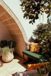 a green bench sitting on a patio with potted plants at Oppure - Masseria Moderna in Polignano a Mare